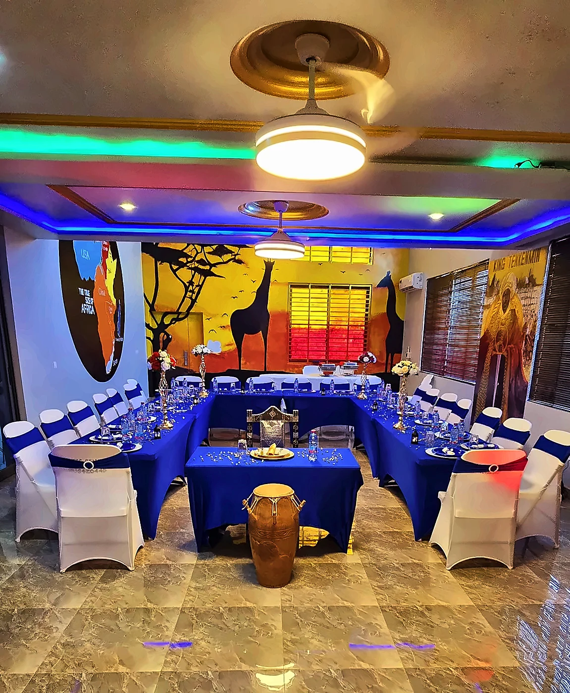 Event hall with blue tables, a traditional drum and African murals