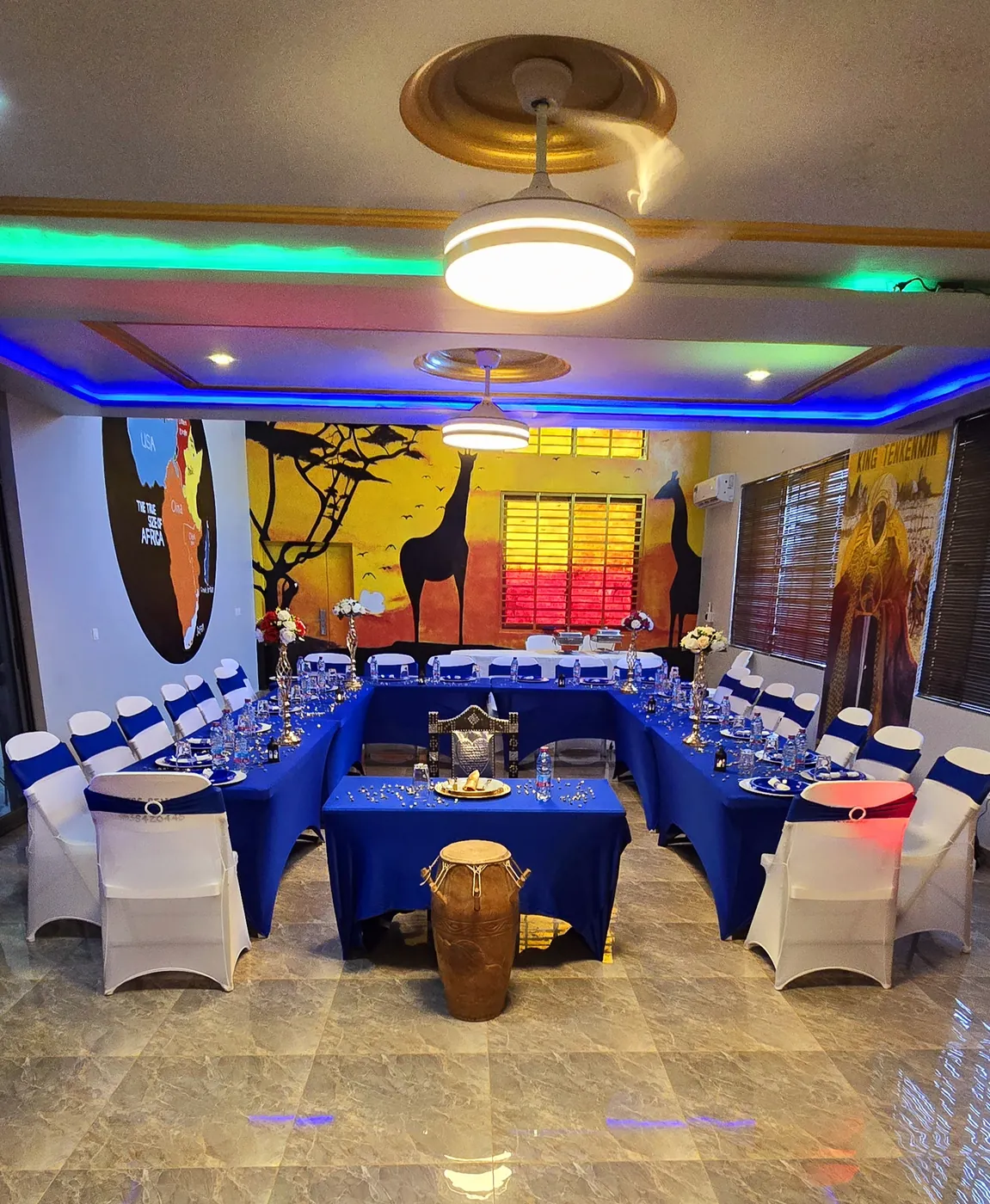 Event hall with blue tables, a traditional drum and African murals